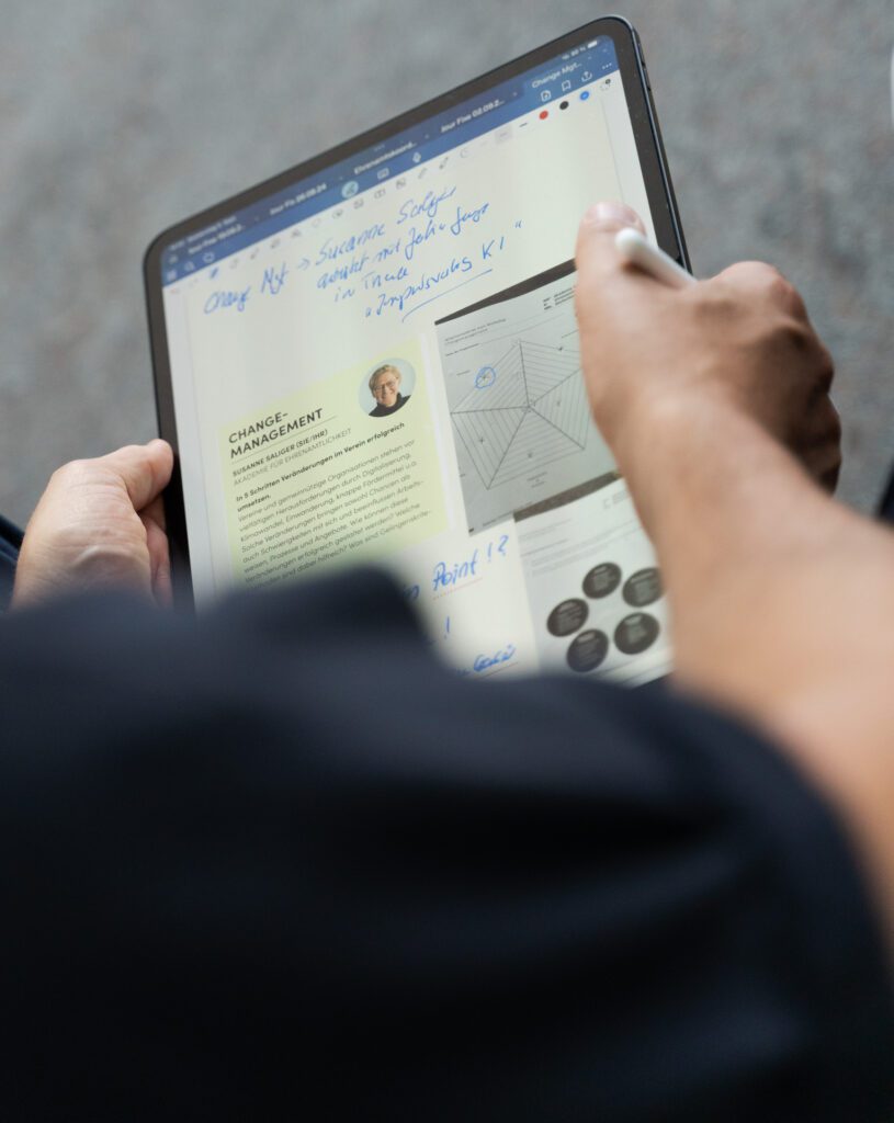 Person hält Tablet mit Text und Diagrammen, auf dem Bildschirm sind handschriftliche Notizen zu sehen